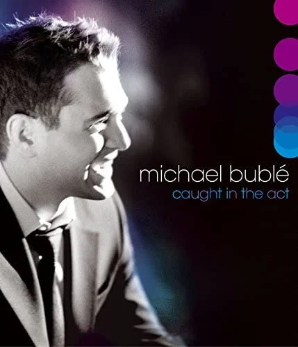 Black and white profile of Michael Bublé smiling, with colored circles on the right and the text "Michael Bublé caught in the act".