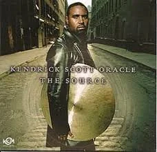 Album cover of Kendrick Scott Oracle 'The Source' featuring a man standing in an urban street holding a large bag.