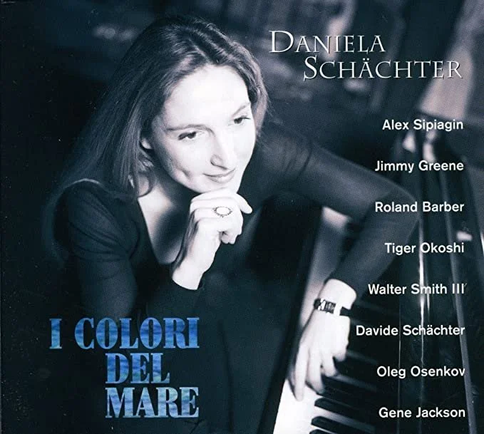 Cover of a music album featuring Daniela Schächther sitting at a piano, with a list of musicians including Alex Sipiagin, Jimmy Greene, Roland Barber, Tiger Okoshi, Walter Smith III, Davide Schächther, Oleg Osenkov, and Gene Jackson.