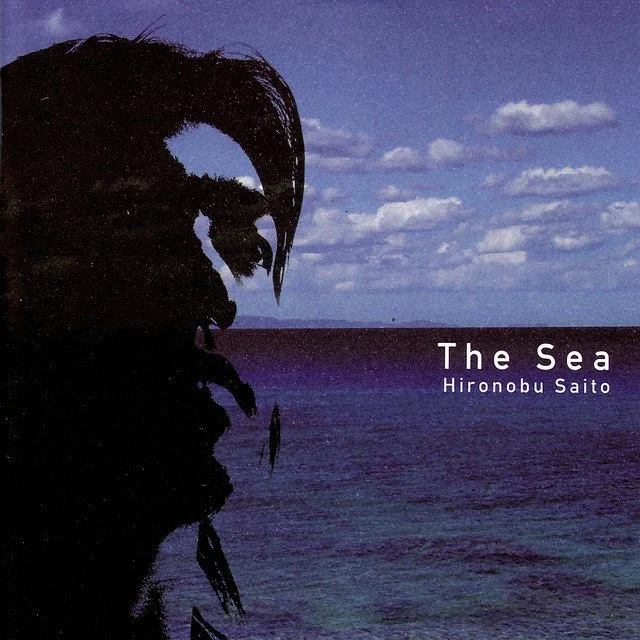 Silhouette of a person's profile against a seascape with a cloudy sky, representing the album cover for 'The Sea' by Hironobu Saito.