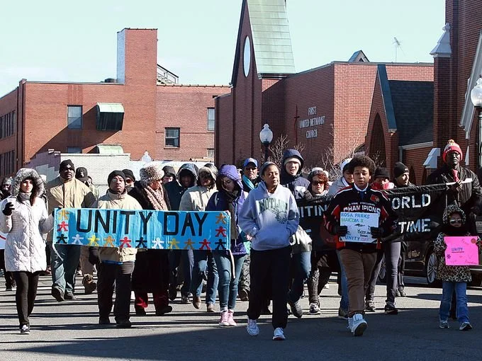 A group of community members march together with posters and a previous Unity Day March.