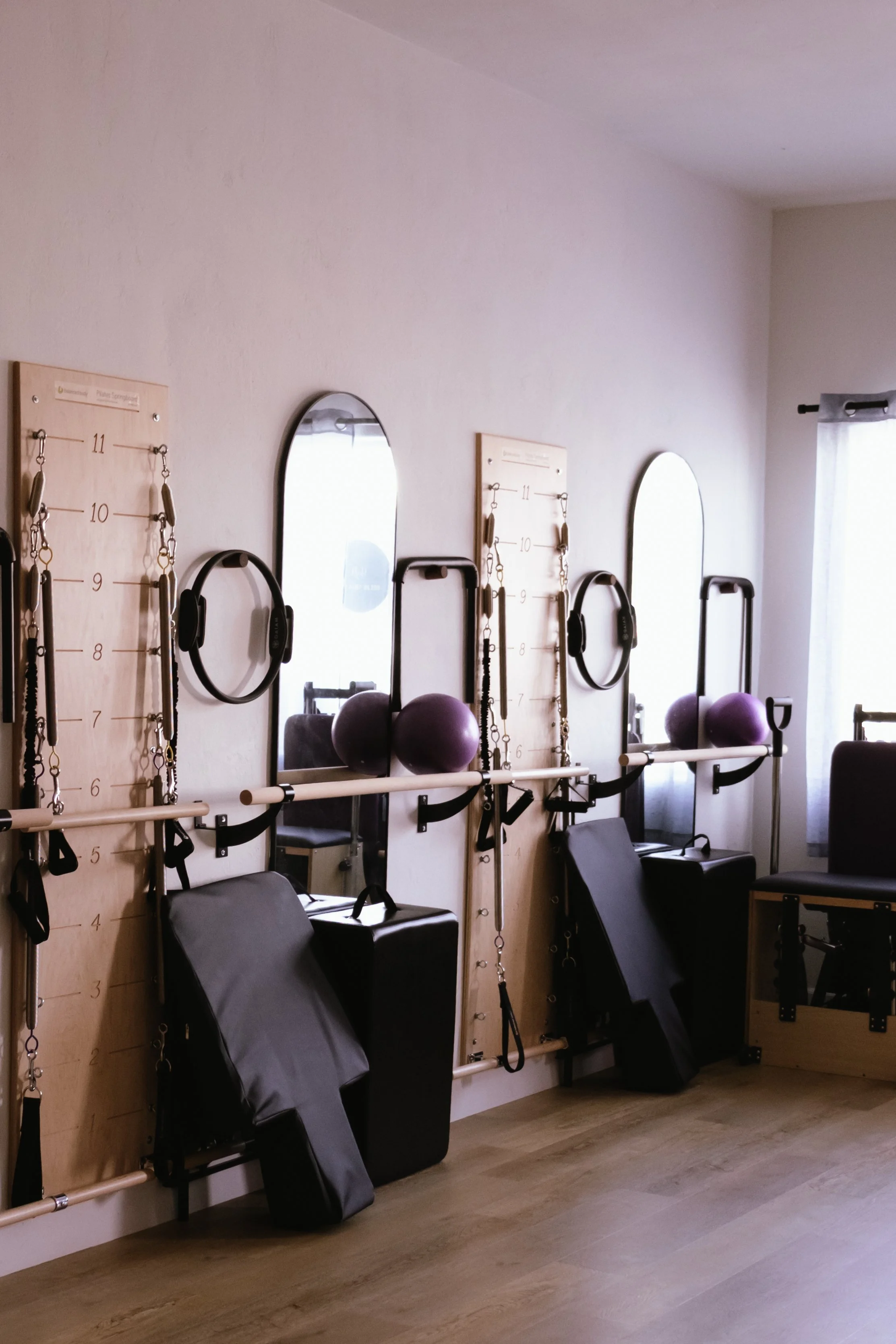 Sound therapy room with mirrors, purple exercise balls, headsets, and Pilates reformer equipment.