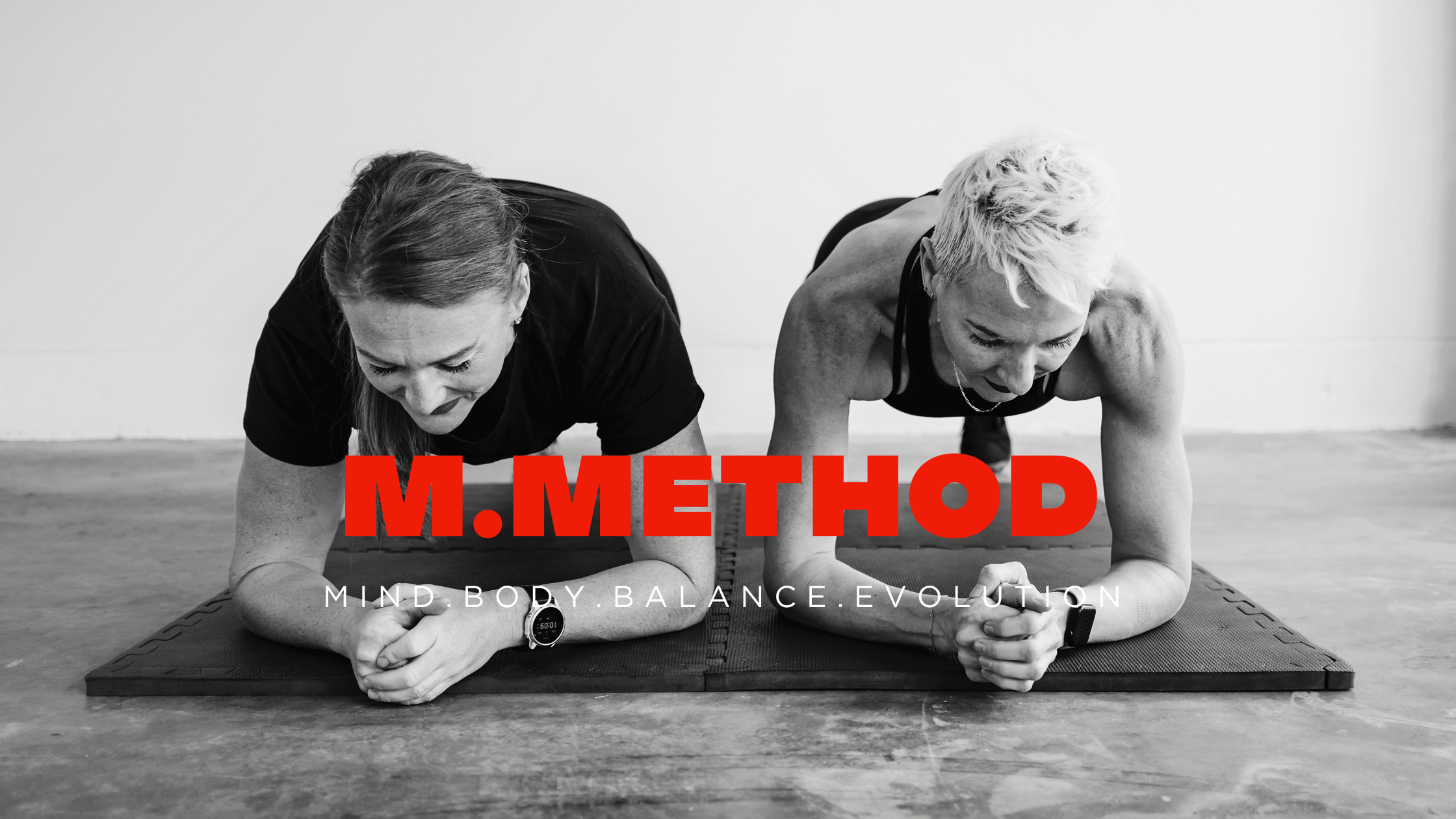 Two women doing plank exercise on a mat, black and white photo with bold red text "M.METHOD" and white text "MIND.BODY.BALANCE.EVOLUTION".