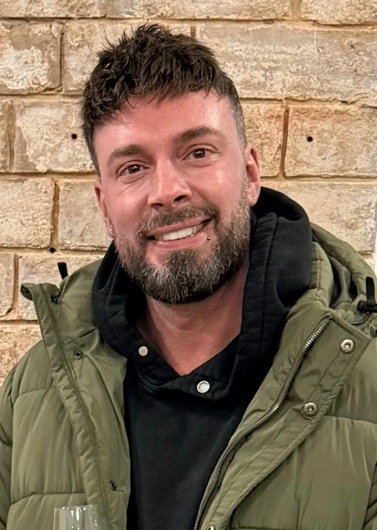 brown haired man smiling in front of a wall, this is ben