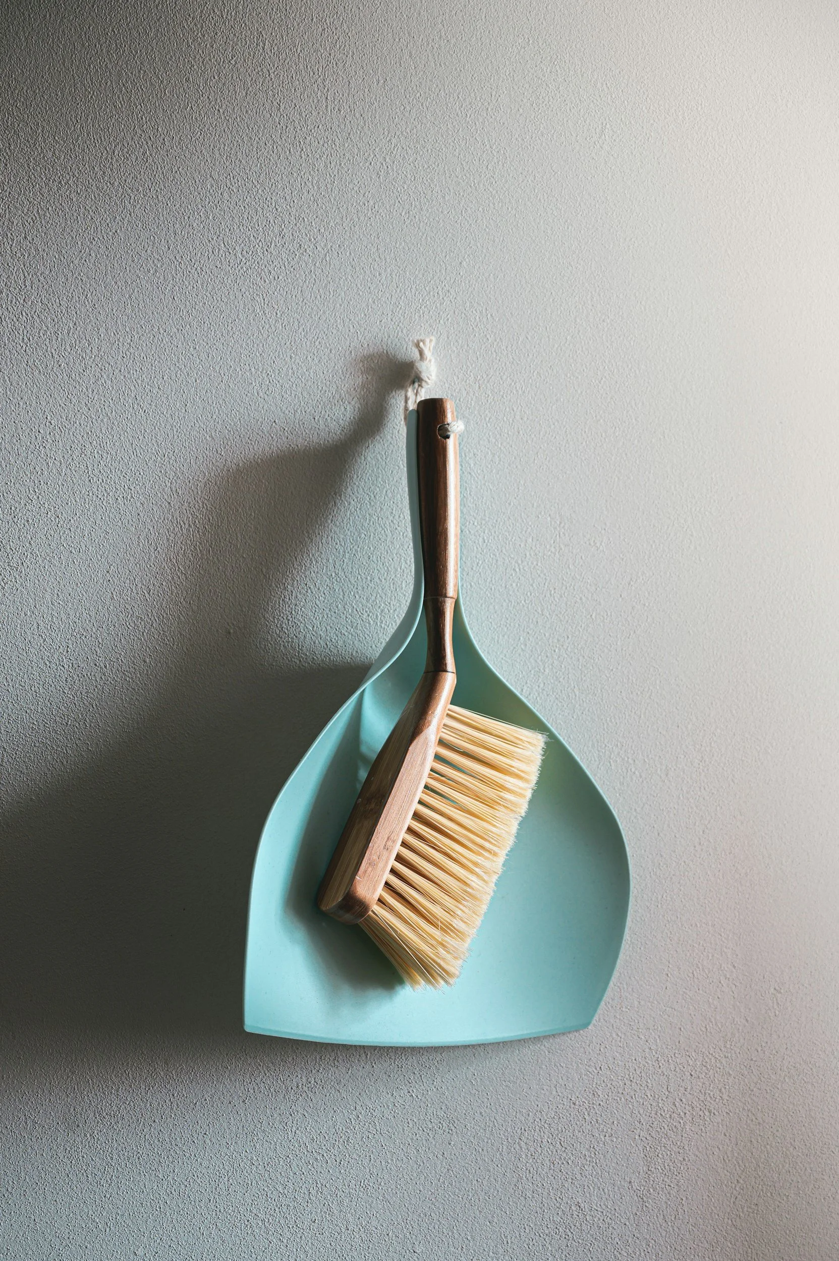 A broom and dustpan placed on a textured gray surface.
