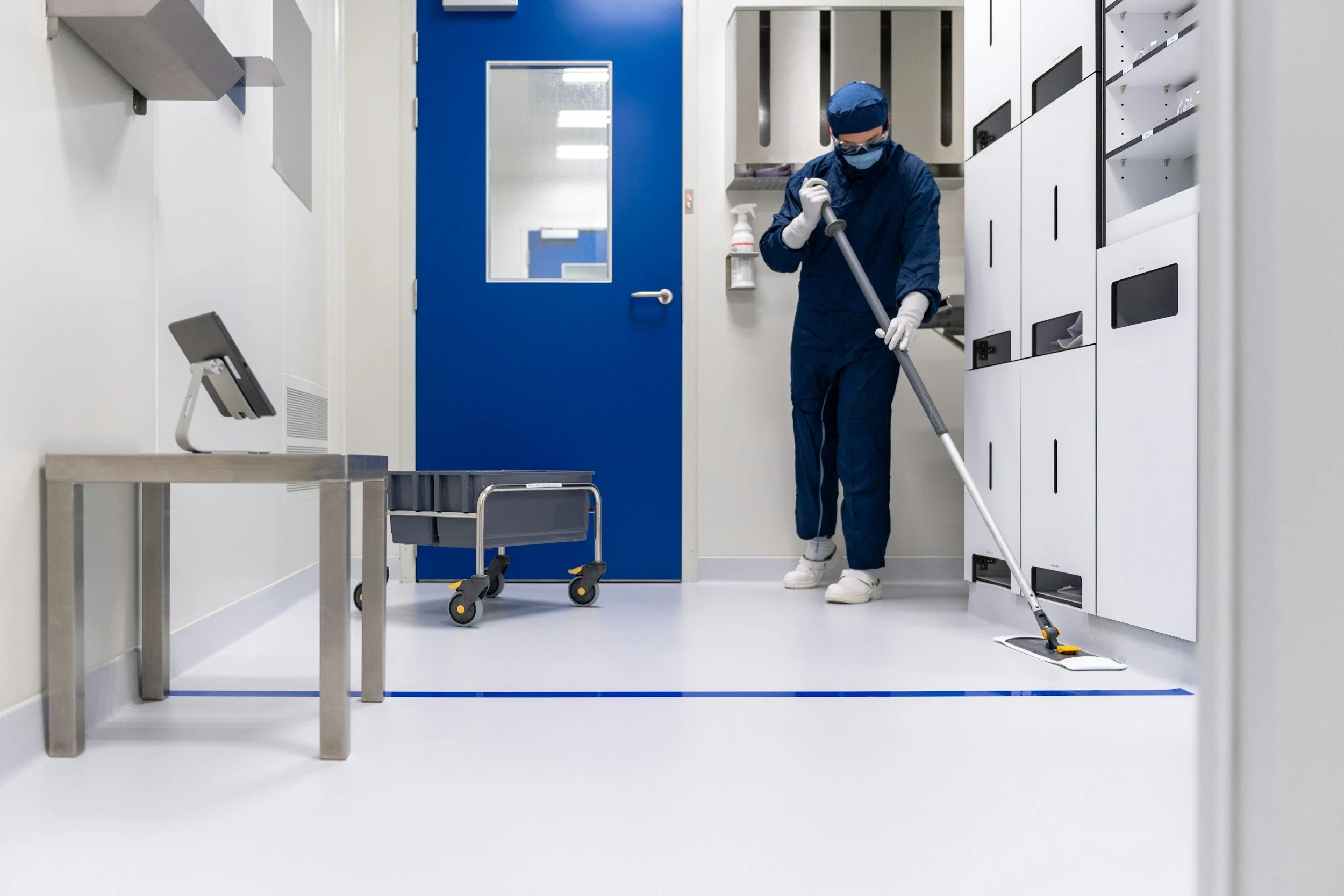 A healthcare worker mops the floor in a hospital room.
