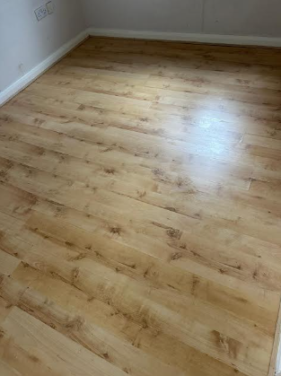 Empty room with light wood flooring and white walls.