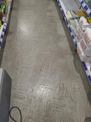 Empty grocery store aisle with shelves on sides and a tiled floor.