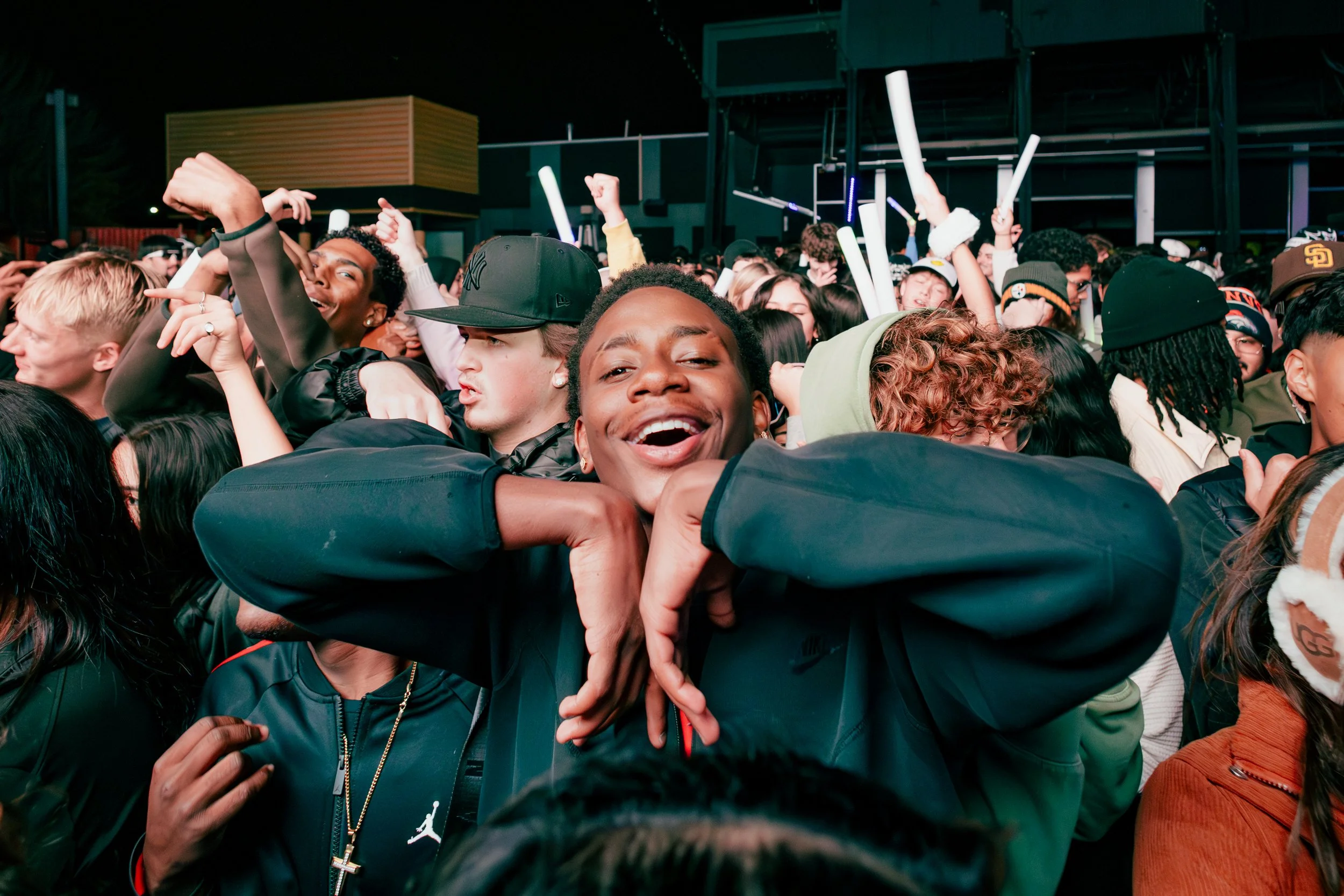 People dancing and celebrating at a crowded outdoor music concert or festival at night.