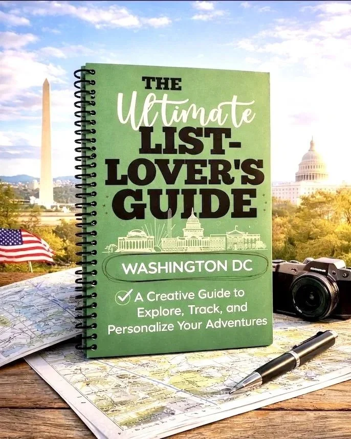 A green booklet titled "The Ultimate List-Lover's Guide:  Washington DC" sits on a map, with a pen and camera with the Washington monument and Capitol building in the background.