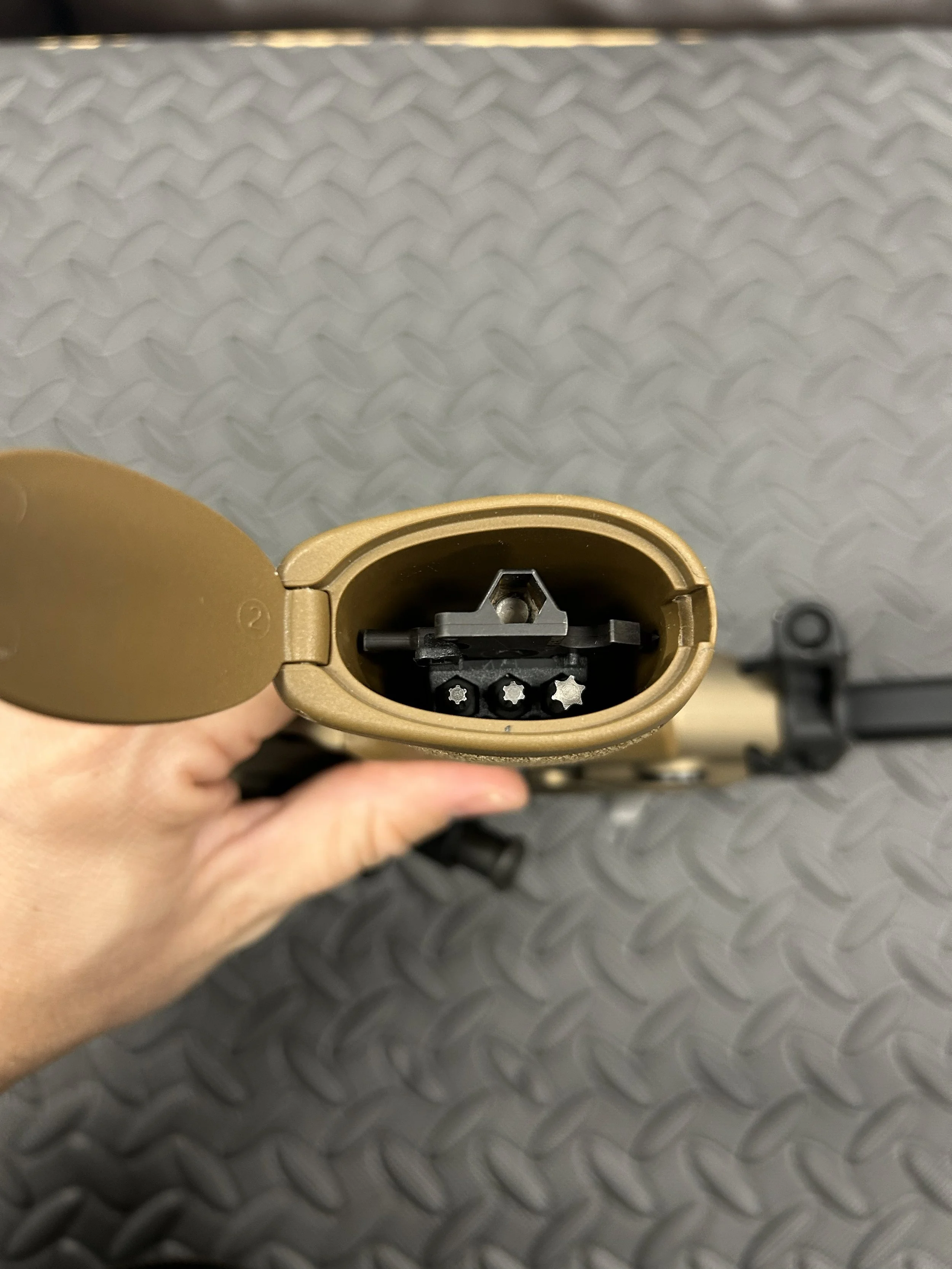 Top view of an opened firearm magazine showing the inside with black and silver chamber components, held in a person's hand.