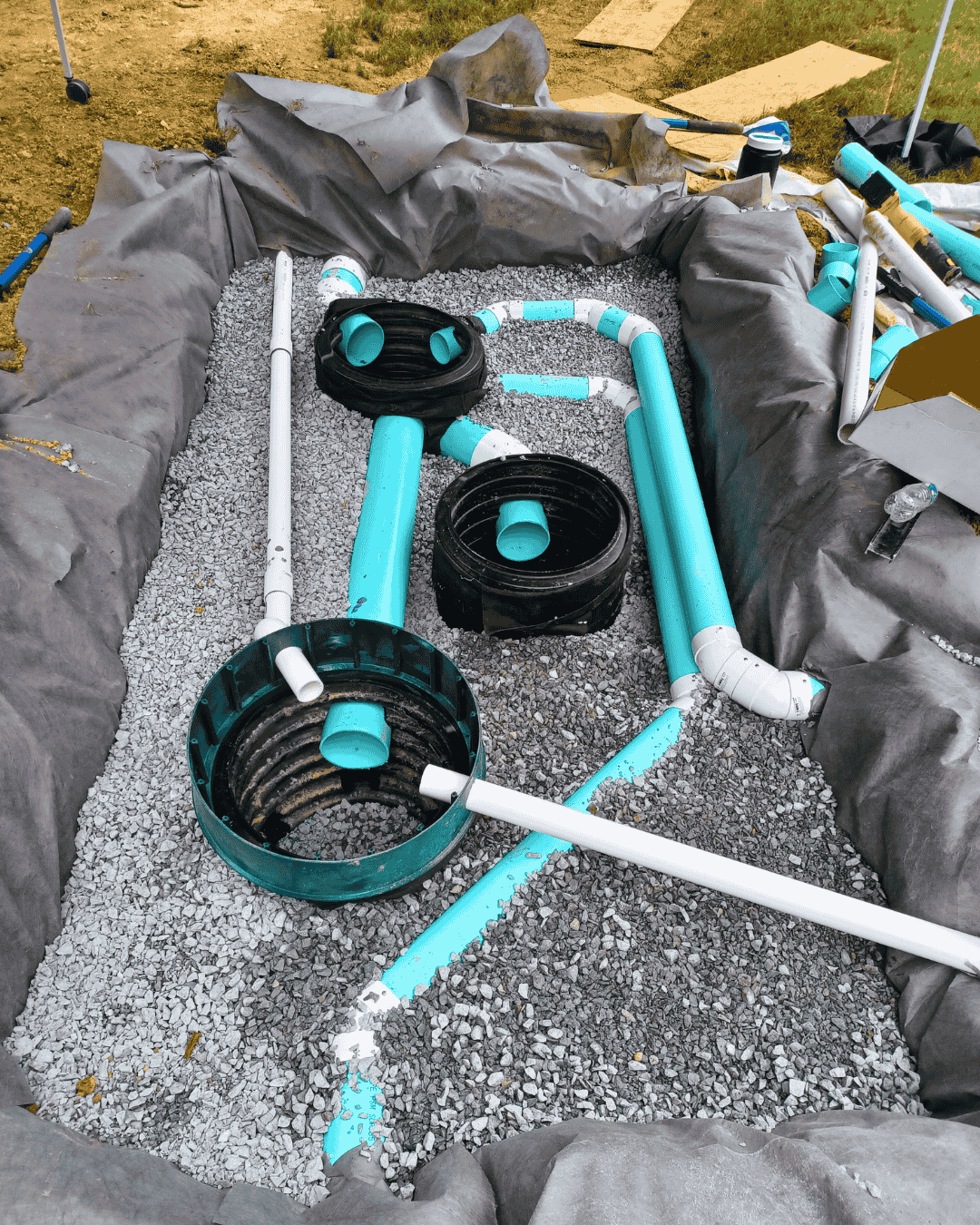 Drainage system components and access ports set in gravel during installation—residential yard drainage project in Greensboro, NC.