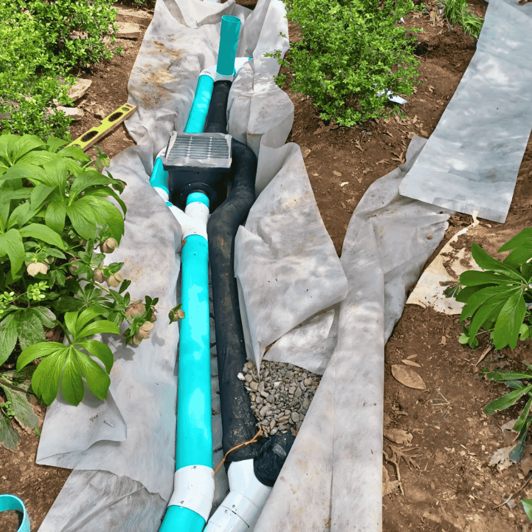 Fabric-lined trench with solid PVC drainage pipe installed beside landscaping—non-invasive yard drainage solution in the Triangle Area, NC.