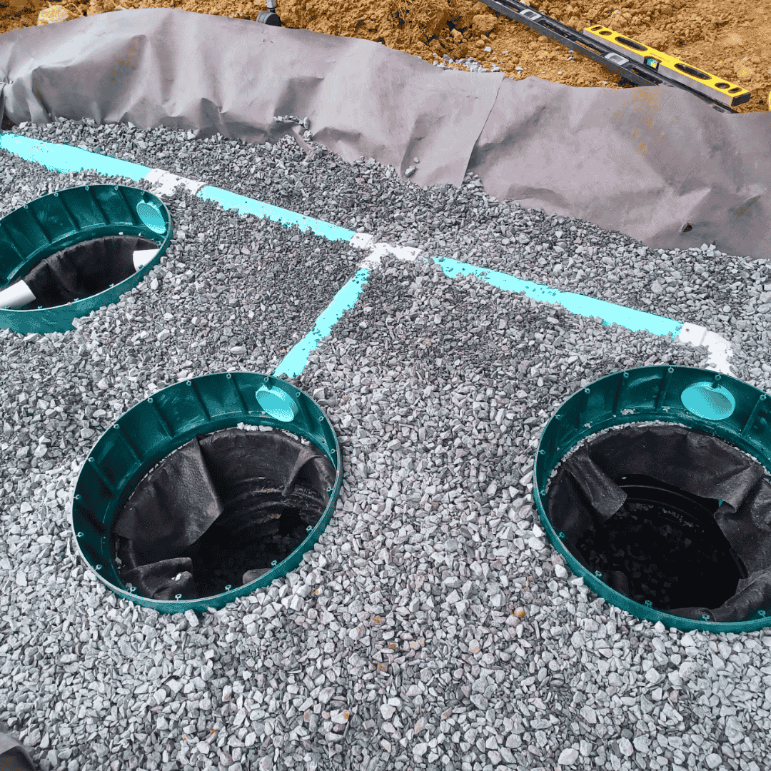 Round drainage access ports set in gravel for a residential drainage system—catch basin and yard drainage installation in Greensboro, NC.