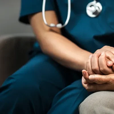 Nurse with scrubs on comforting a lady