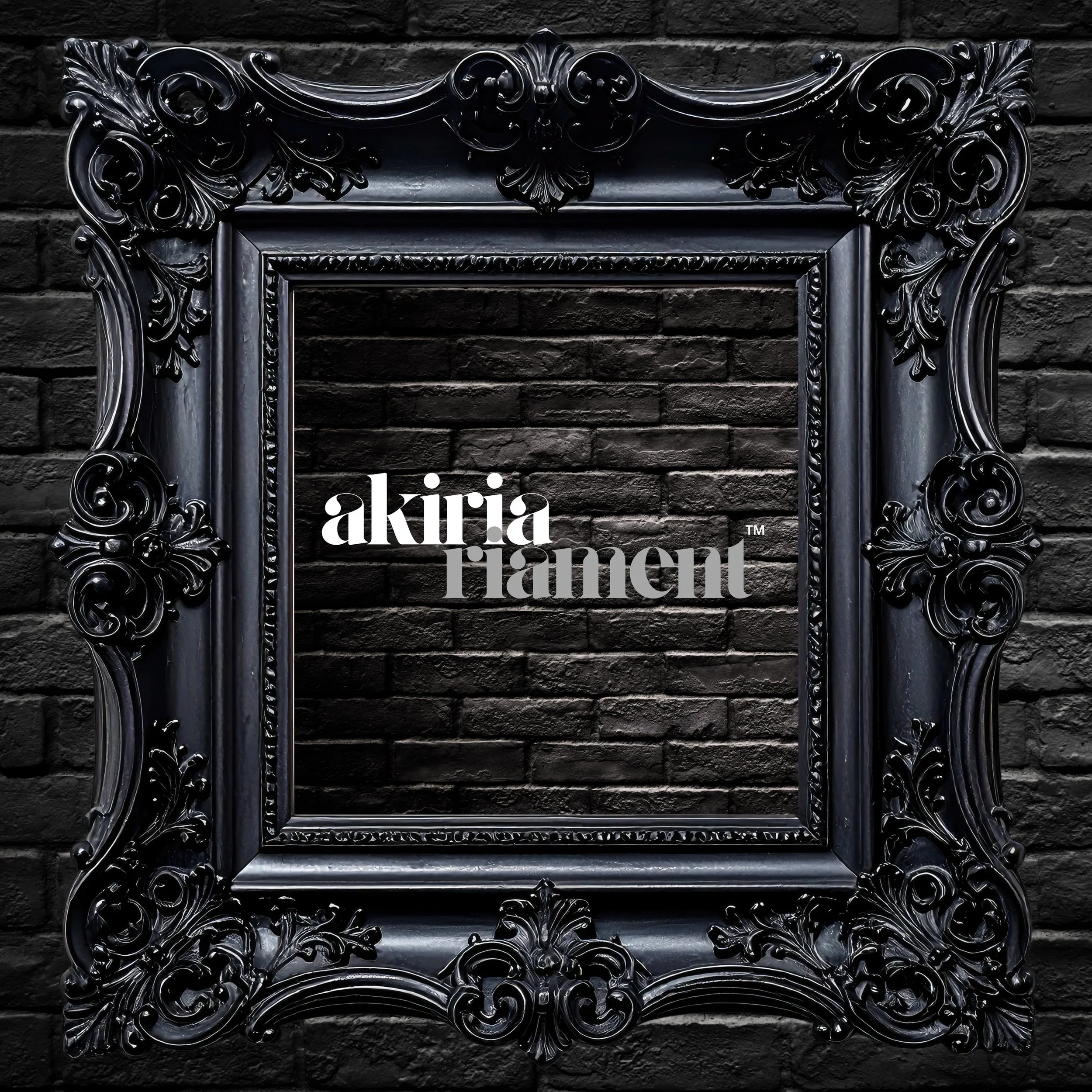 An ornate black picture frame with intricate scroll designs, mounted on a dark brick wall, featuring the text 'akiria raiment™' in the center.