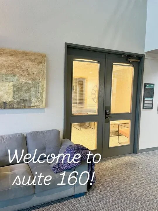 Interior view of a room with a gray sofa, a purple blanket, a painting on the wall, and glass double doors leading to another room. Text overlay says 'Welcome to suite 160!'.