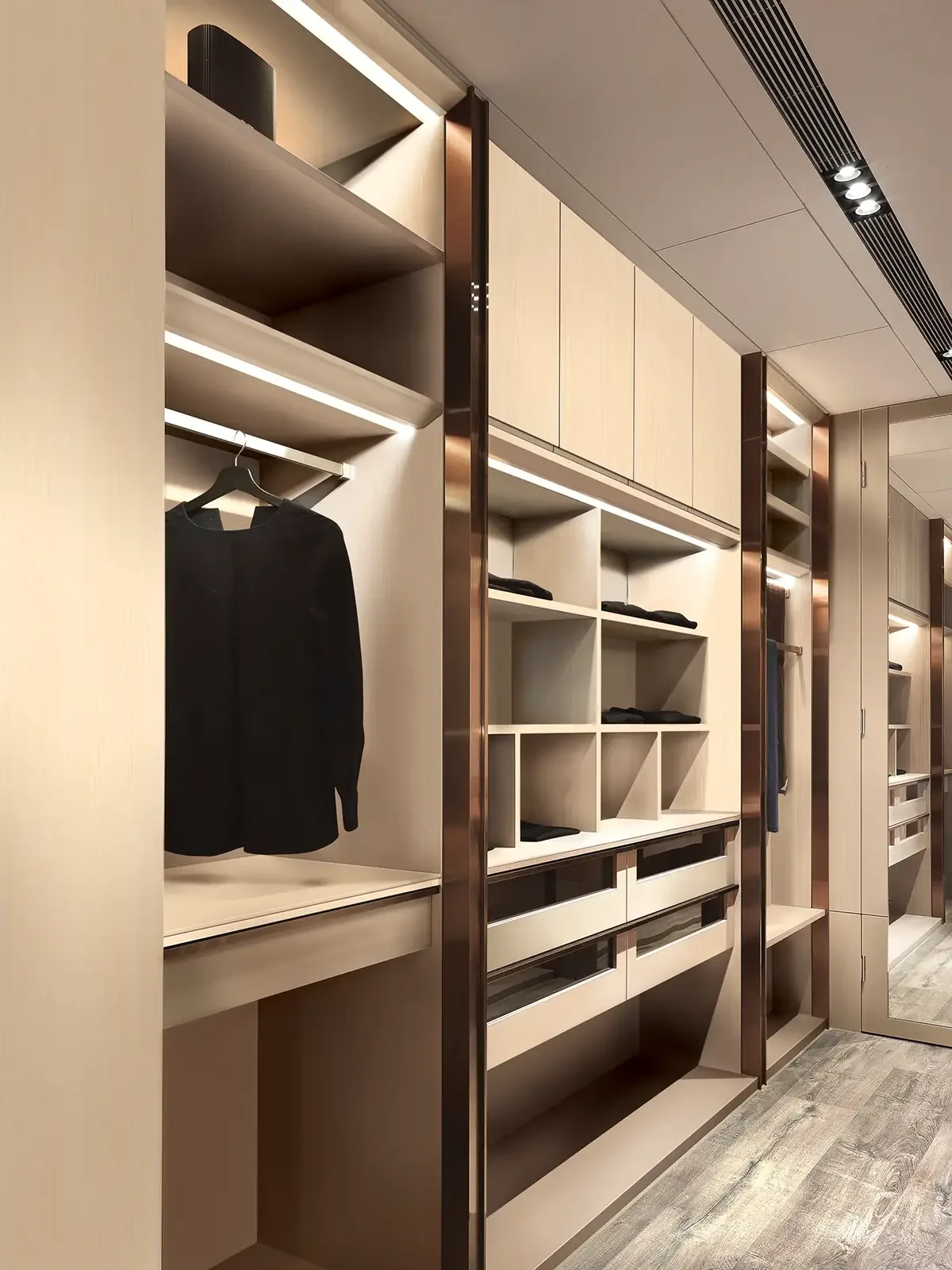 Modern walk-in closet with open shelves, drawers, and hanging space, including a black jacket on a hanger.