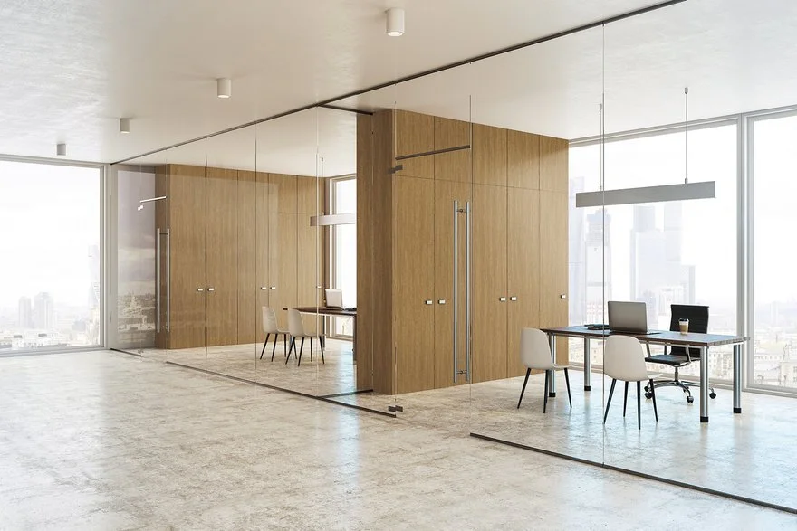 Modern office space with large windows, wooden walls, and glass partitions, furnished with desks, chairs, and office equipment.