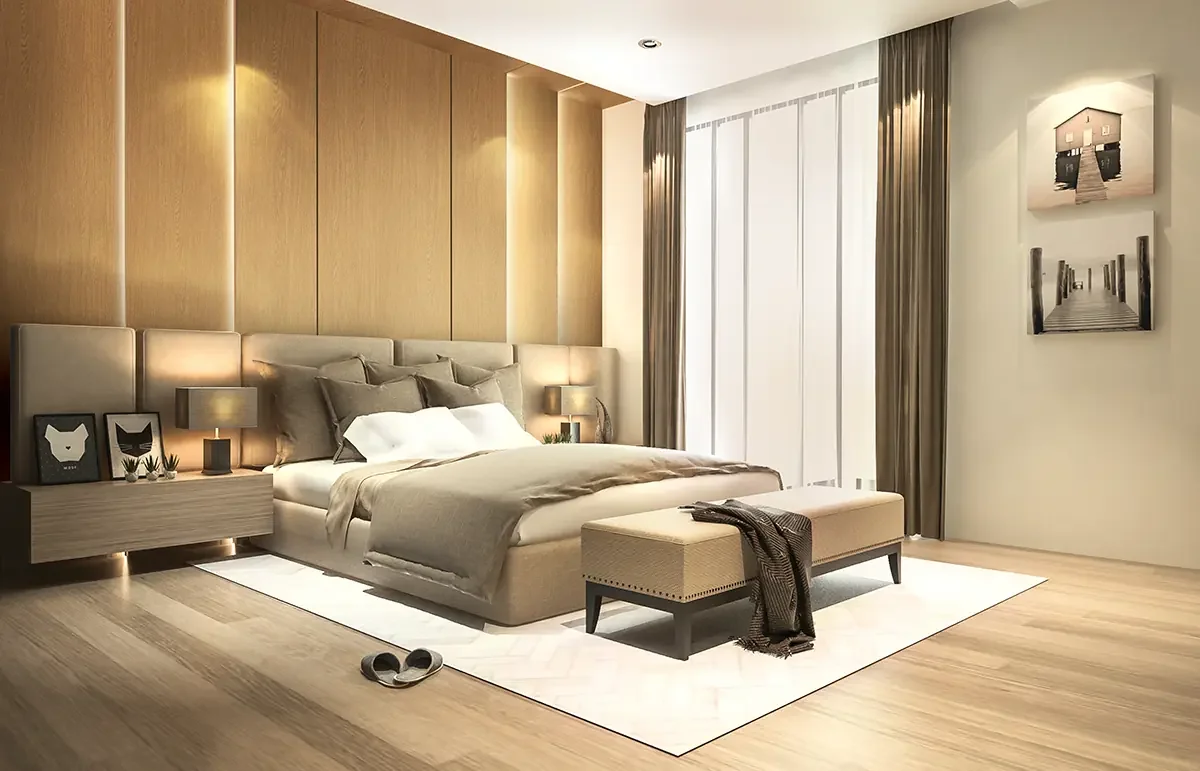 Modern bedroom with beige and gray color scheme, large bed with pillows, two nightstands with lamps, framed artwork on wall, sliding glass doors with curtains, and slippers on wooden floor.