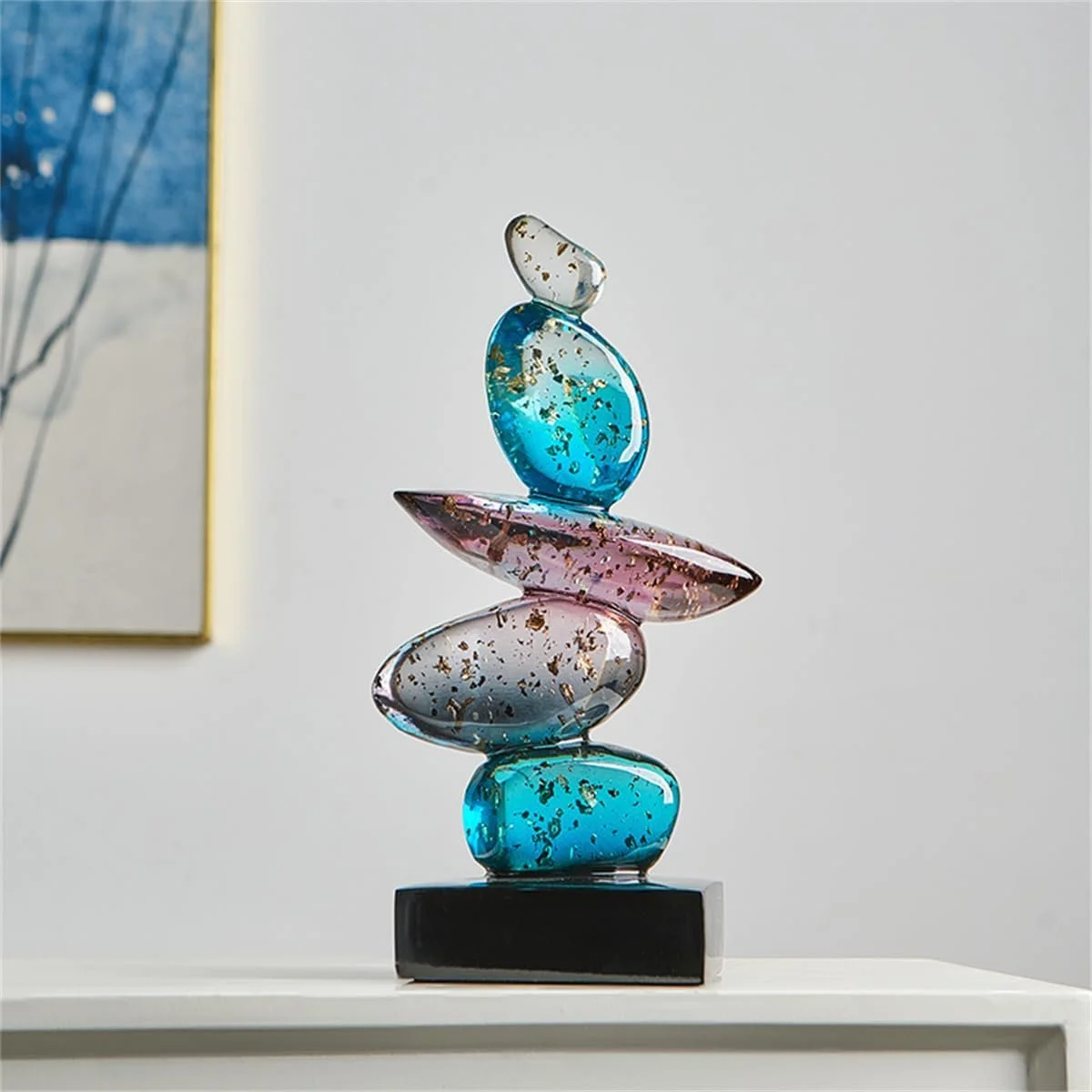 Colorful glass sculpture with five stacked, abstract shaped glass pieces on a black base, decorated with gold flecks, placed on a white surface.