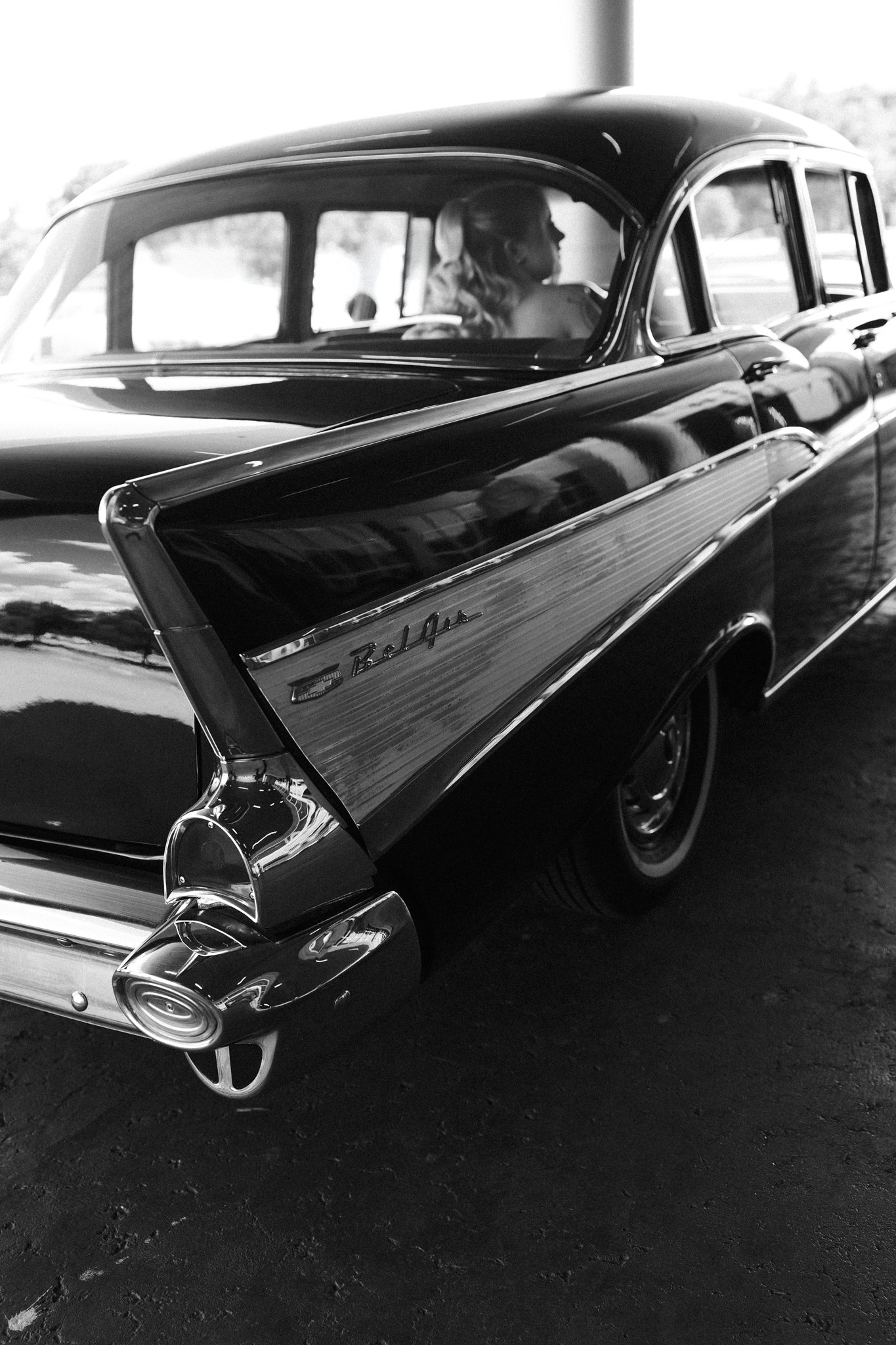 Black and white photo of a vintage Cadillac car with a Dallas bride seated inside, looking out the window.
