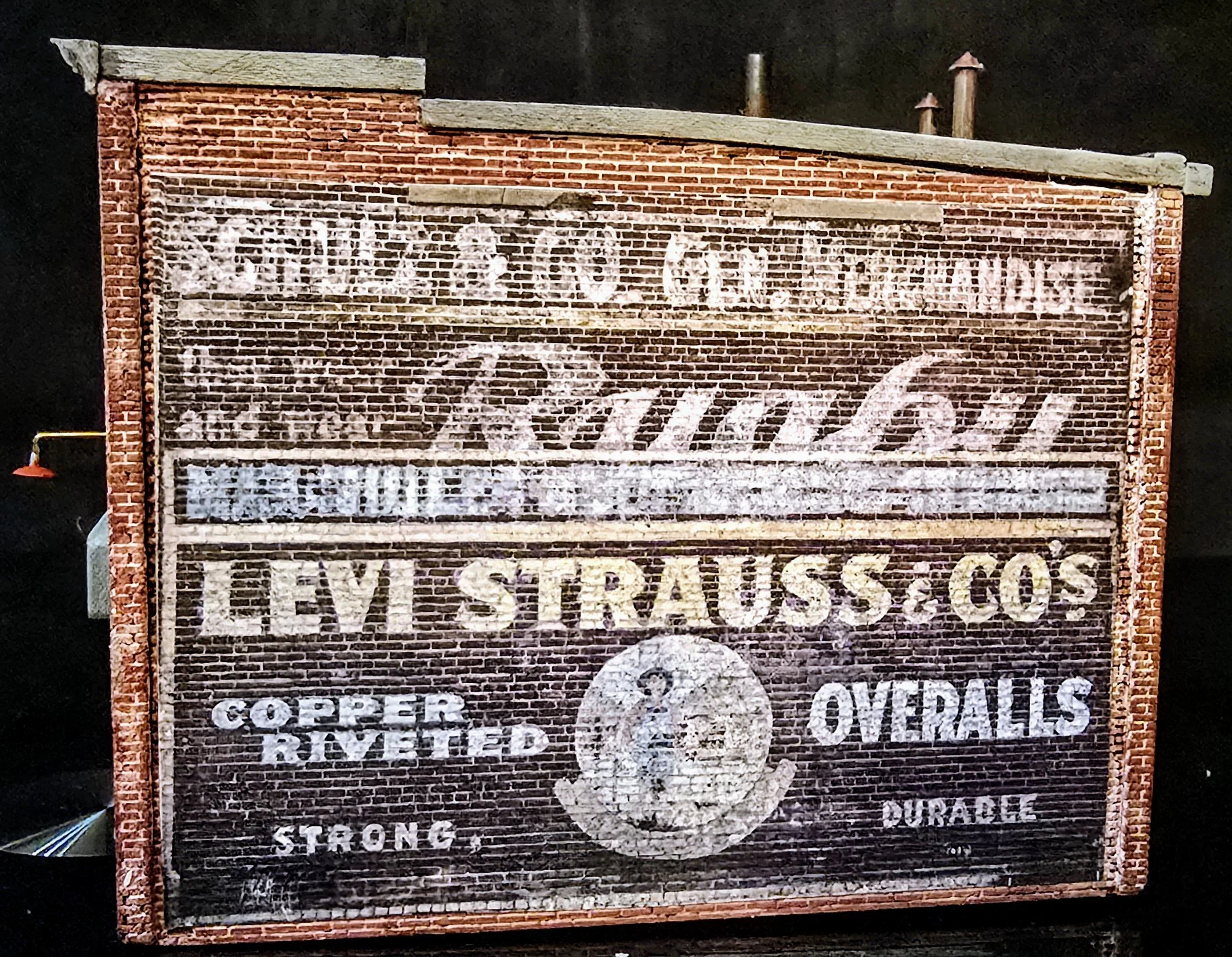 An old brick advertisement sign for Rust-Oleum products, featuring faded white lettering and logos promoting copper and other metal coatings.