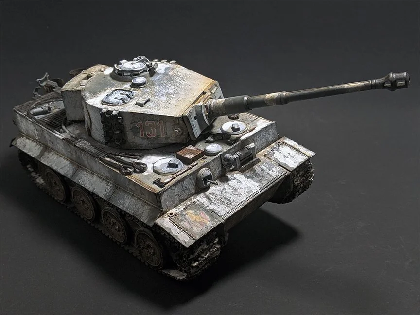 A detailed model of an old, weathered tank with a long barrel, numbers, and markings, placed on a dark surface.