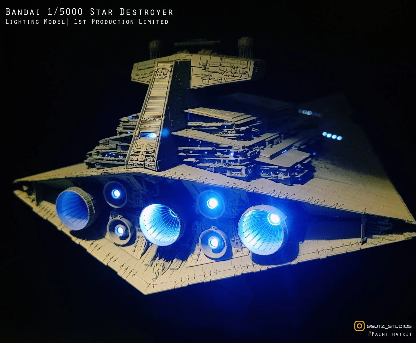 Model of a Battlestar Galactica spaceship with glowing blue engines, detailed with gray and black colors, set against a black background with each engine emitting a blue glow.
