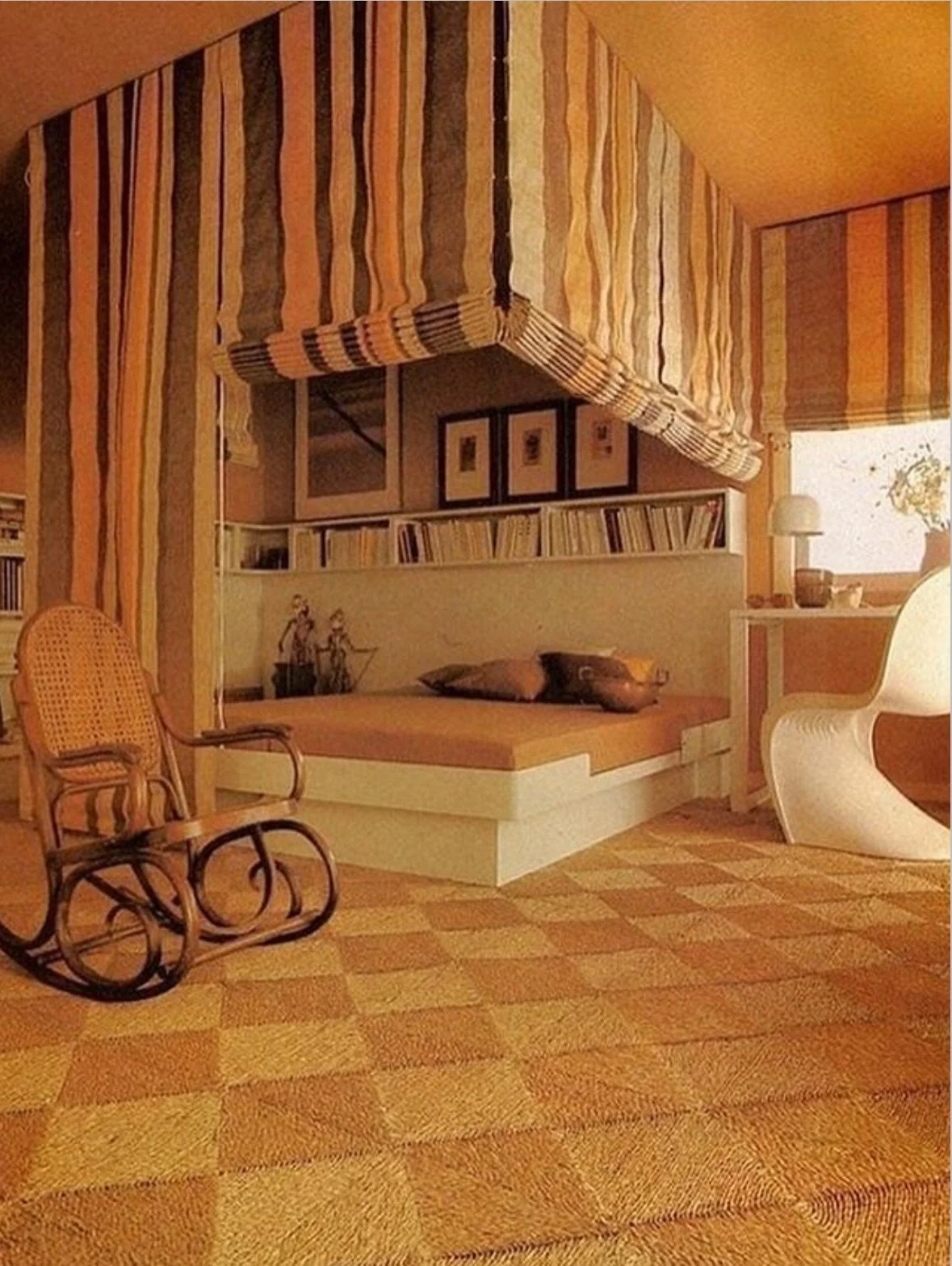 A cozy room with striped walls and ceiling, a white daybed with pillows, a wooden rocking chair, woven carpet, and modern styled white chair near windows with a plant and lamp.