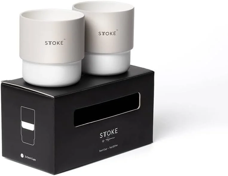 Two white Stoke brand smart coffee cups placed on top of a black Stoke branded box.