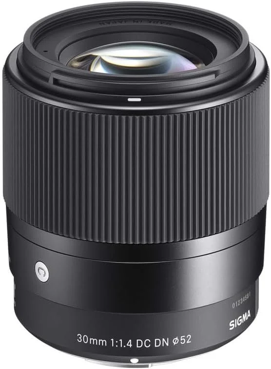 A Sigma 30mm camera lens with a black ribbed exterior and a visible glass element.