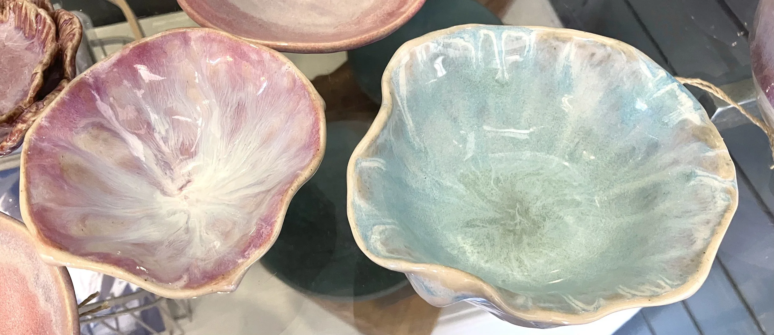 Colorful ceramic bowls with a flower petal shape, in pastel pink and pastel blue-green colors, displayed together.