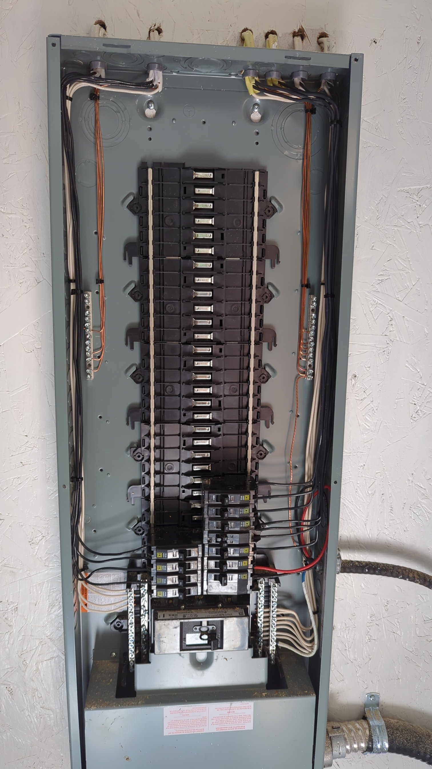 Open electrical circuit breaker panel with multiple switch breakers and wiring.
