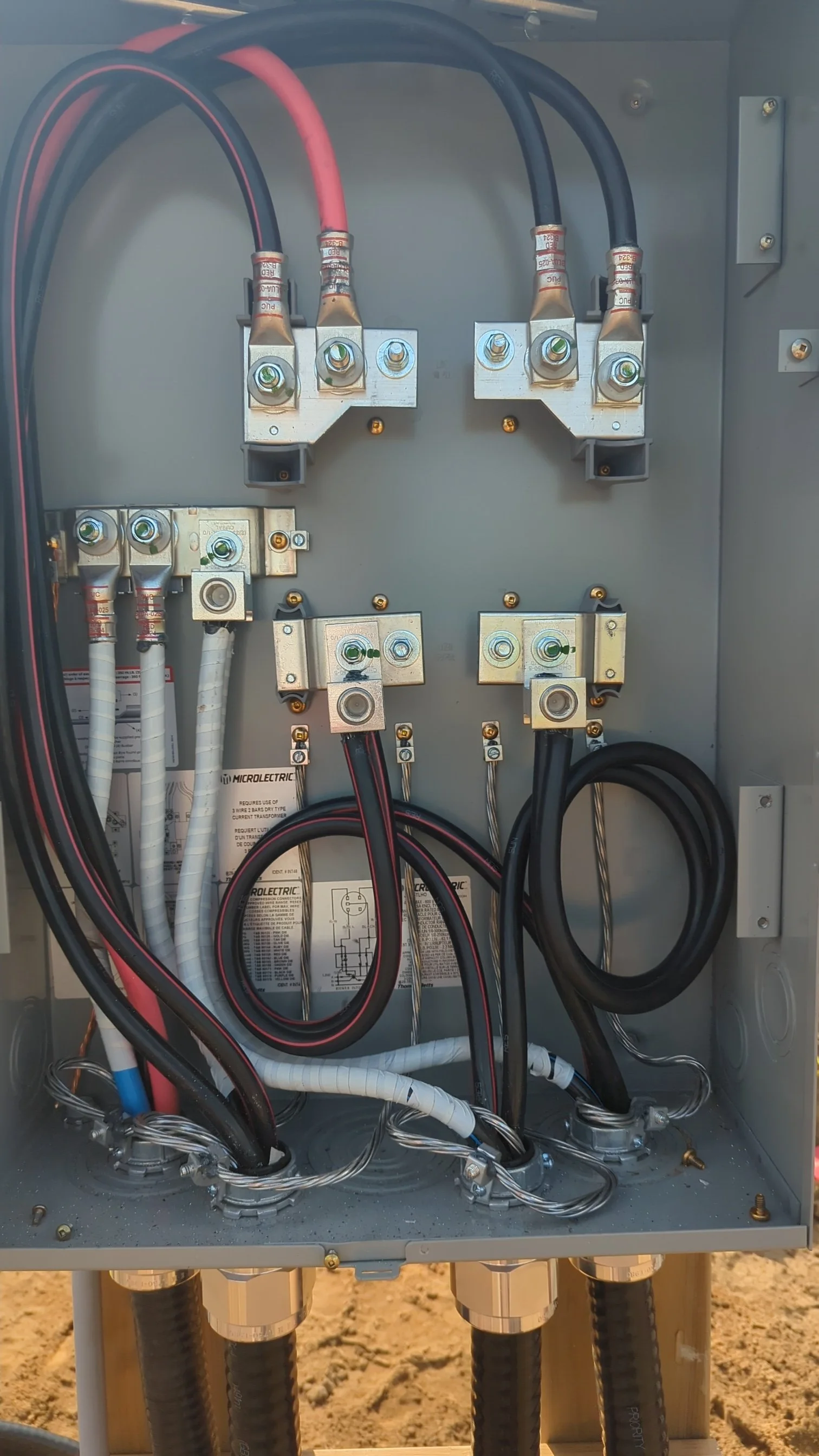 Electrical service panel with multiple wires connected to terminals, mounted outside on a metal box