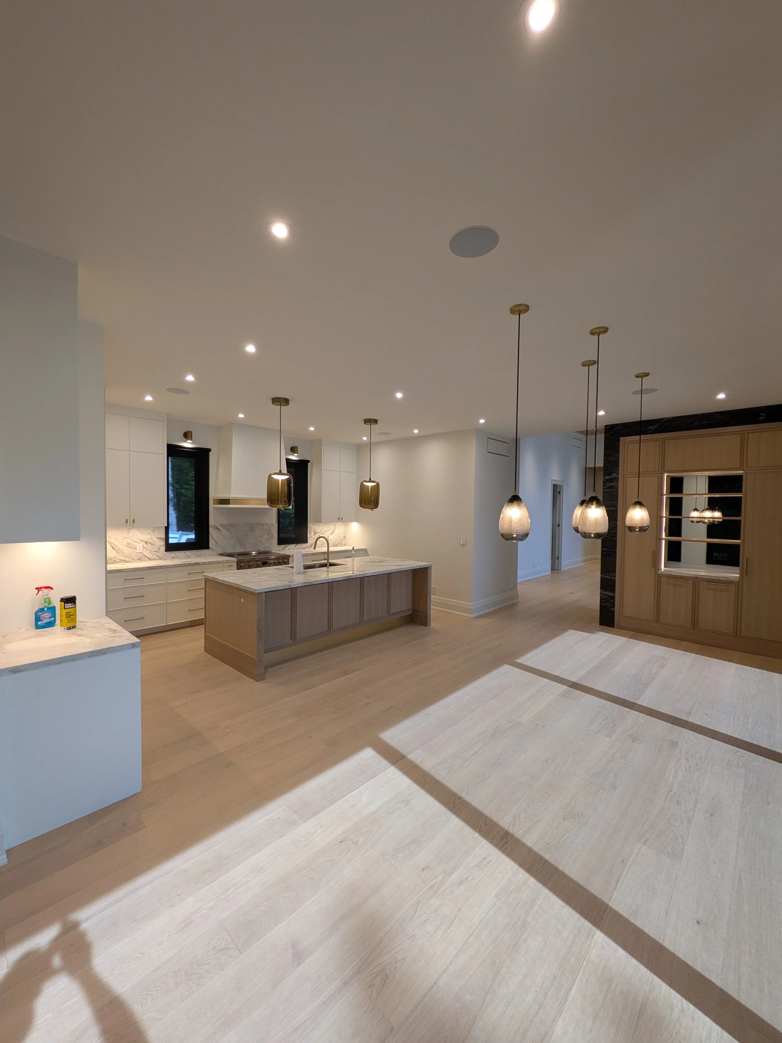 Modern kitchen with white cabinets, a marble backsplash, an island with a wooden base, and gold pendant lights.