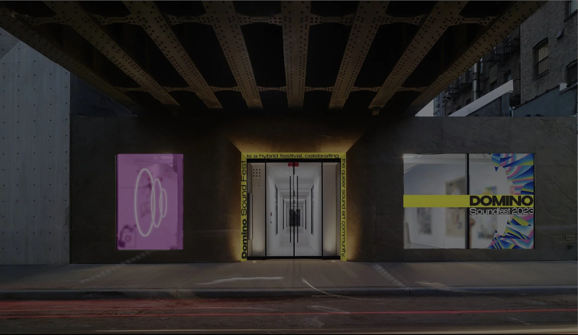 Entrance to the Domino Soundfest 2023 with illuminated digital posters on either side of the door, yellow and black signage indicating a hybrid festival celebrating the future sound art community, and a tunnel-like corridor leading into the venue.