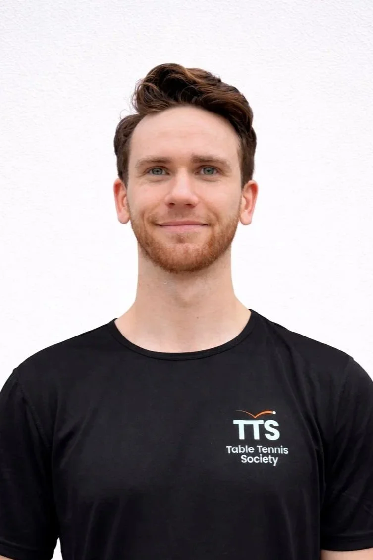 Table Tennis Coach with black t shirt looking into camera.