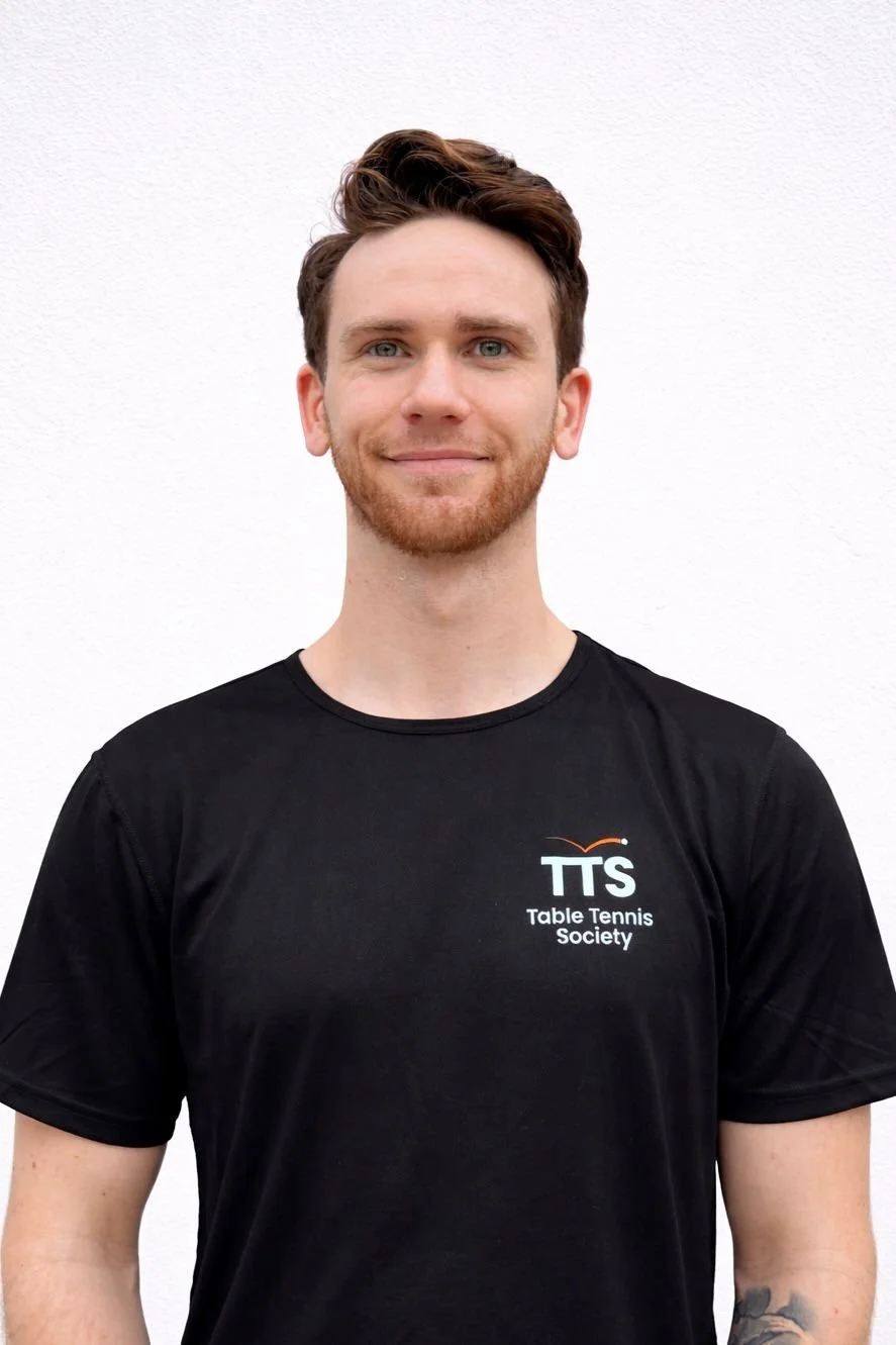 Table Tennis Coach with black shirt looking into the camera.