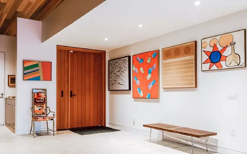 Breathtaking entryway with stunning artwork, a custom wooden minimalist bench and terrific pot lighting expertly installed