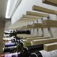 Wine bottles lying on a shelf with wooden dividers in between, in a wine storage area.