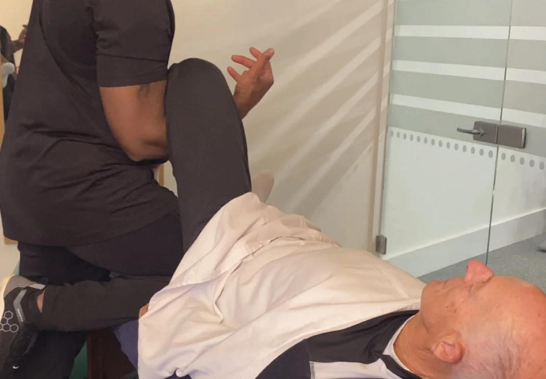 A person receiving a leg massage from a massage therapist in a clinical setting.