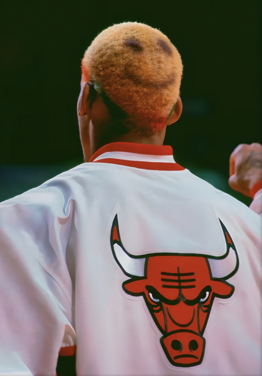 Une personne vue de dos portant une veste blanche avec un logo de taureau rouge et noir à l'arrière, sur fond sombre.
