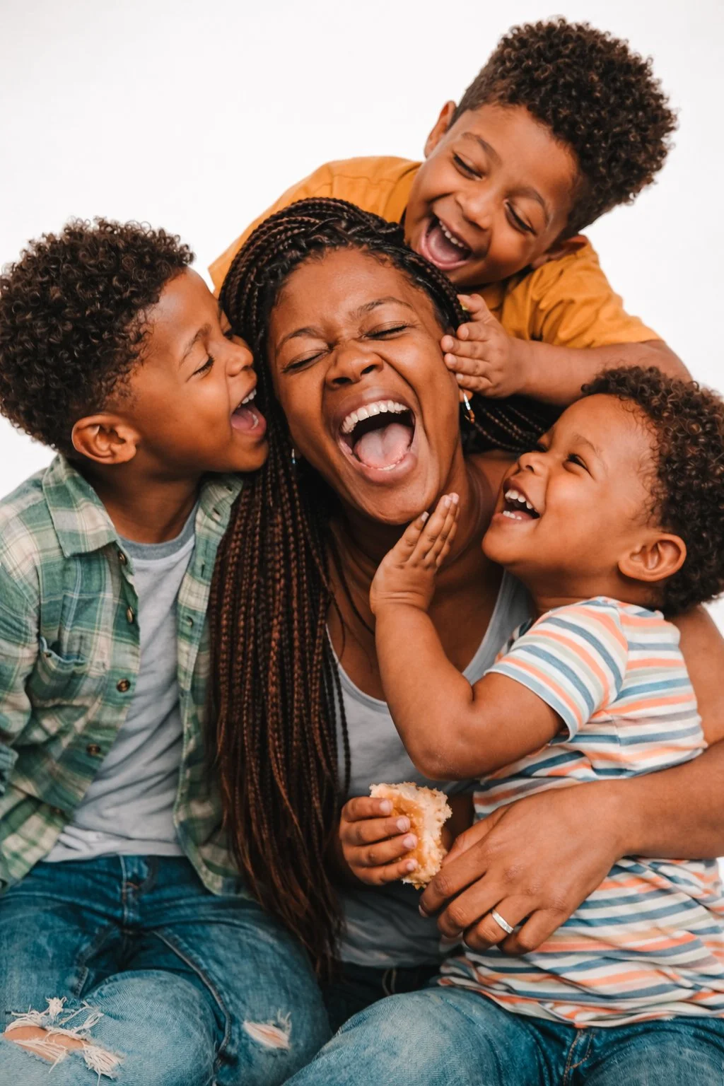 A woman surrounded by three children, all smiling and laughing, sharing a joyful moment together.