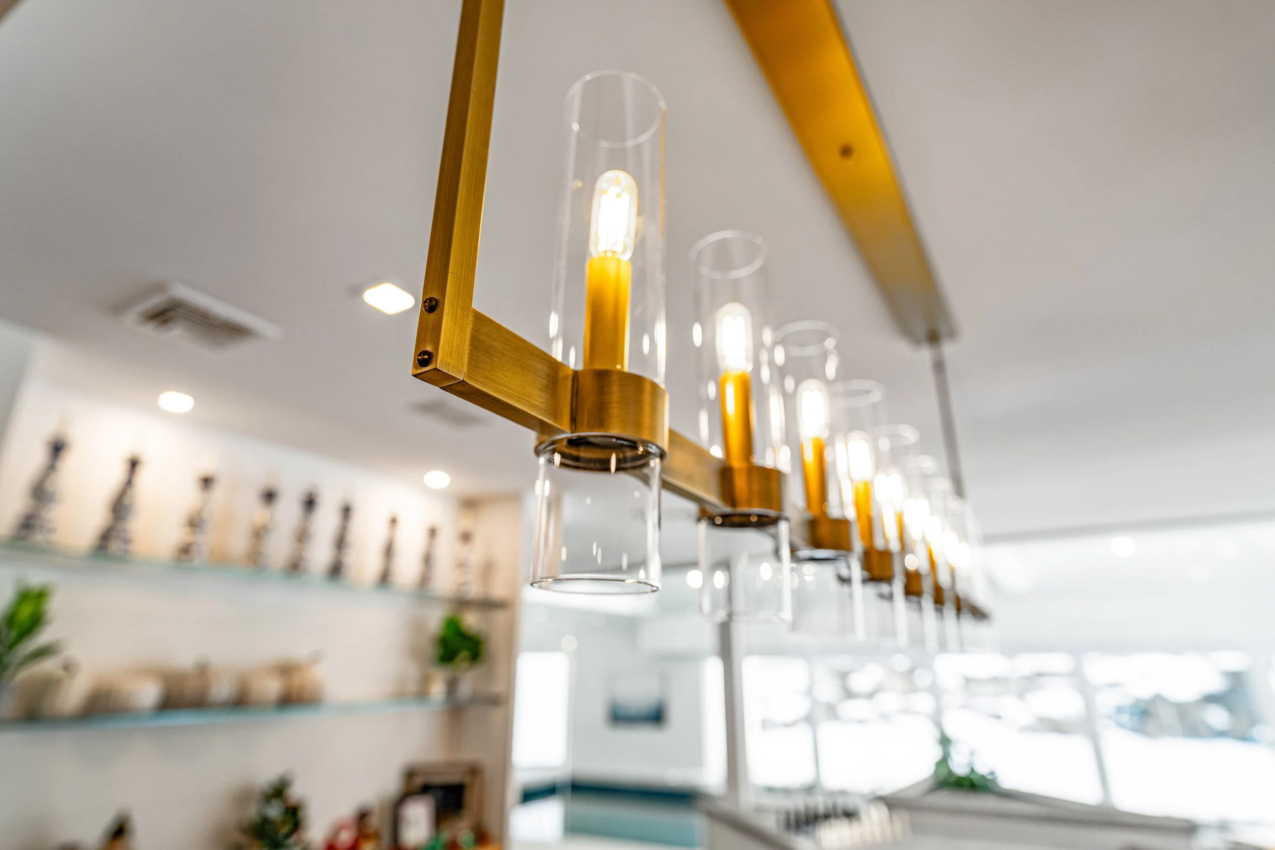 Modern pendant lights with glass covers and gold fixtures hanging from a ceiling in an interior space.