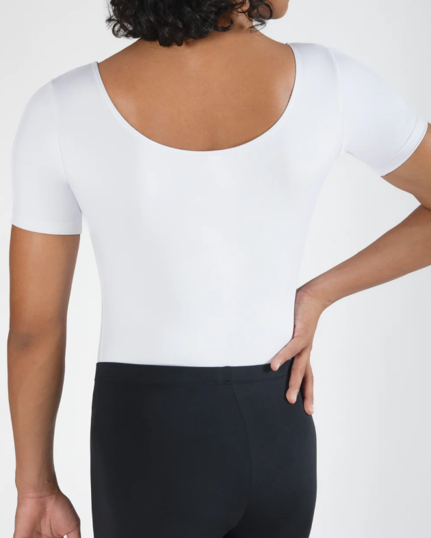 Back view of a woman wearing a white short-sleeve top and black pants, with her right hand on her waist.