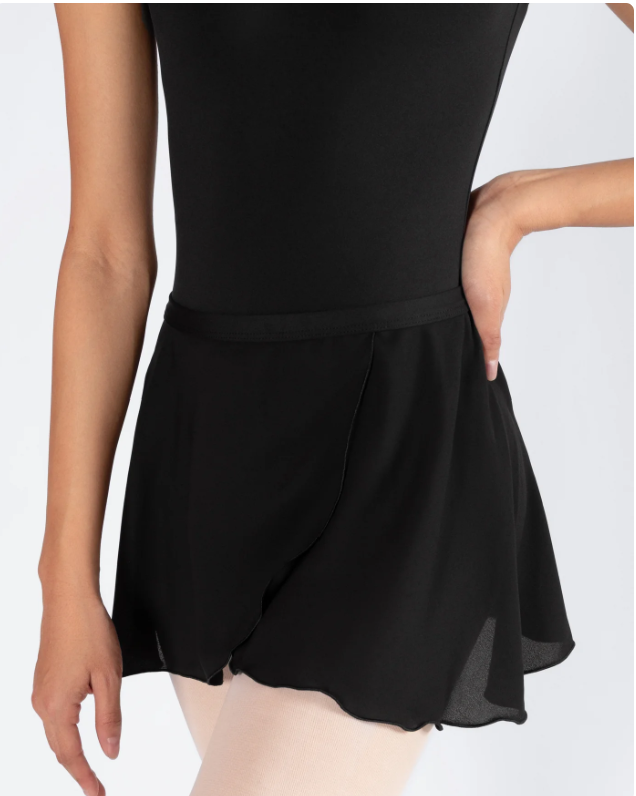 A person wearing a black leotard and black dance shorts, with one hand on their hip.