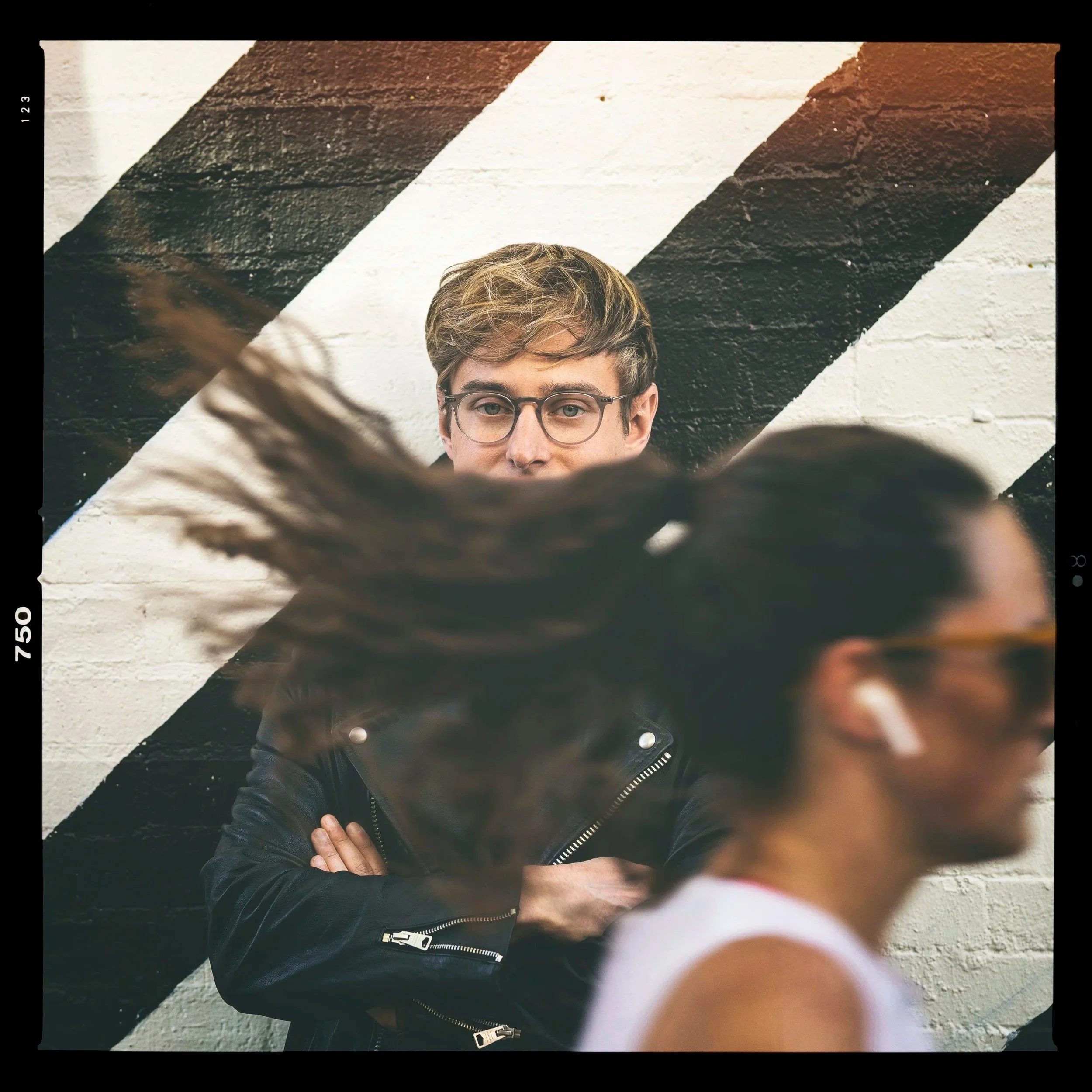 man passes by another man looking at his long hair