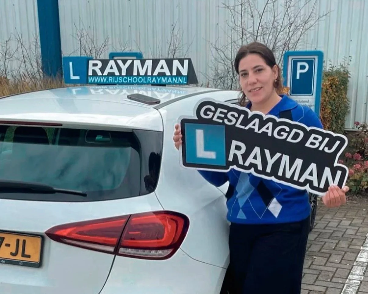 Vrouw met lesauto en bordje die zegt dat haar rijopleiding bij Rayman geslaagd is.