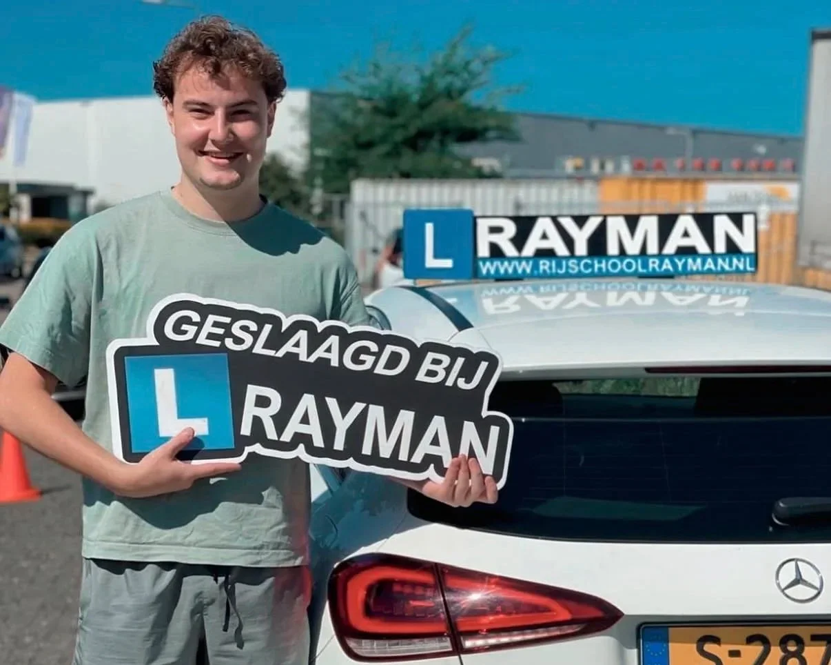 Gelukkige man die een verkeersschool cadeau geeft, staande naast een witte auto met een rijopleiding bord en een verkeersschool reclamebord